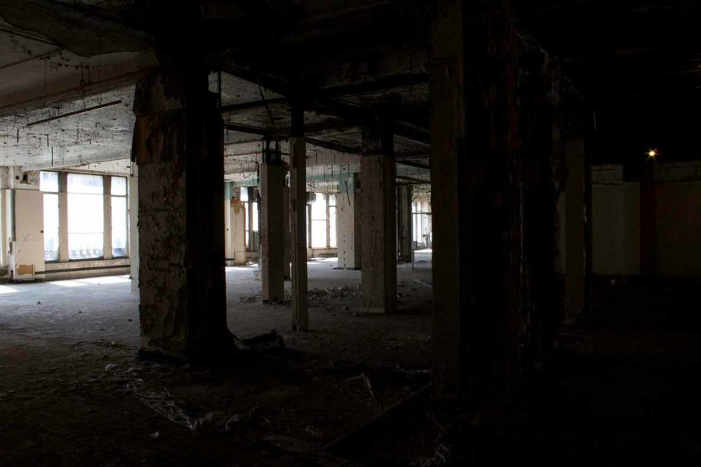 Photo. The interior of an abandoned building, with interesting interplay of light and shadow from the windows.