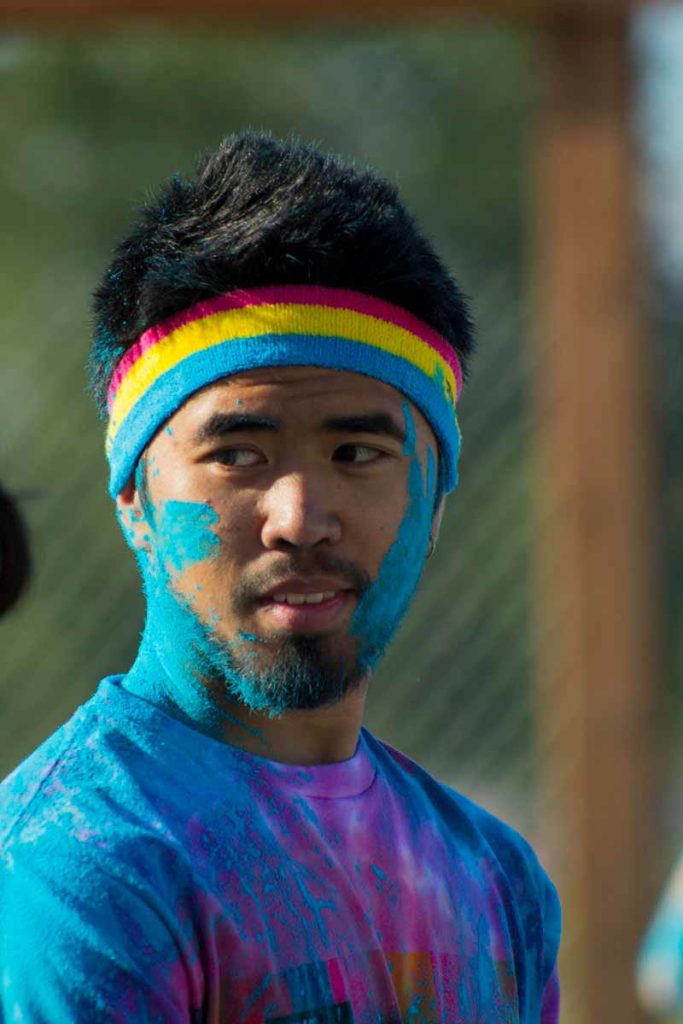 Photo. A young man covered in bright colored chalk at a festival.